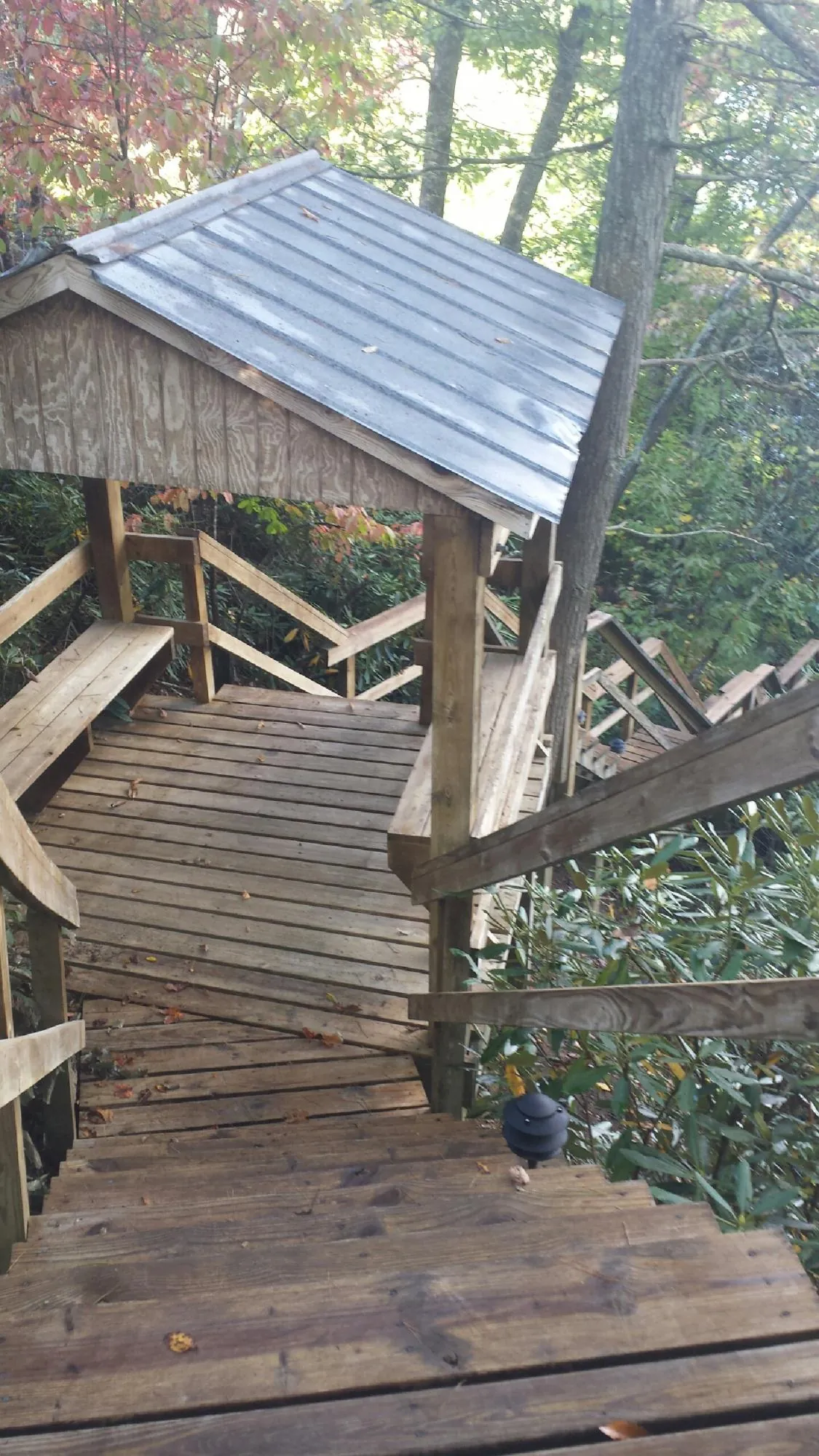 Metal roofed shelter over wooden steps on a wooded walkway — Skylight Repair & Installation work by our crew in Louisville