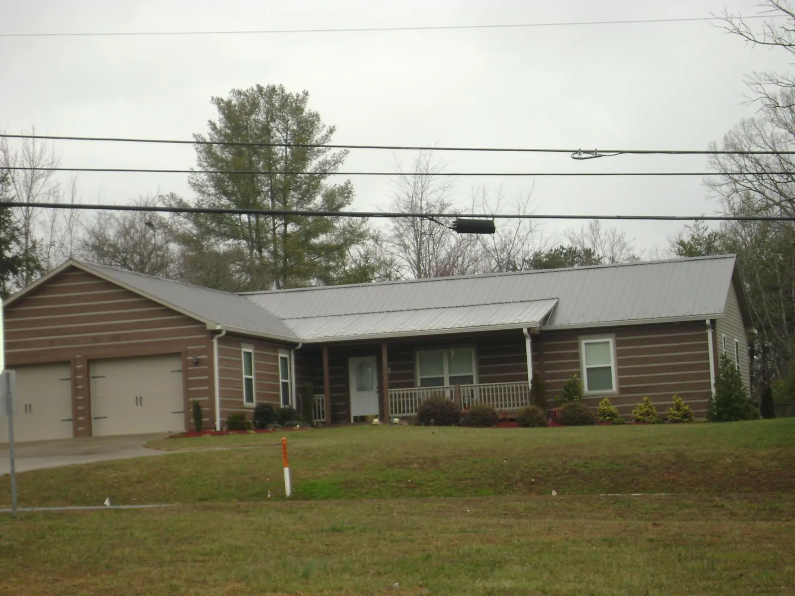 Gray metal roof on a log sided ranch home with a front porch in Louisville